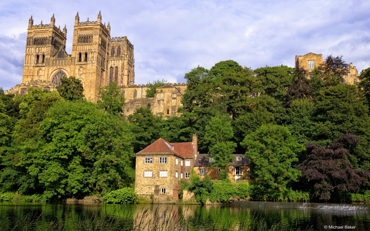 Durham Cathedral rising above wooded riverbanks and the River Wear