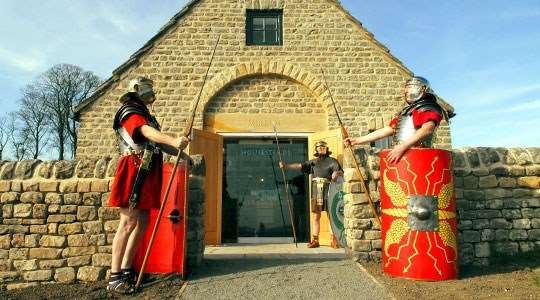 Costumed Roman legionaries standing either side of the entrance to the Housesteads Roman Fort visitor centre